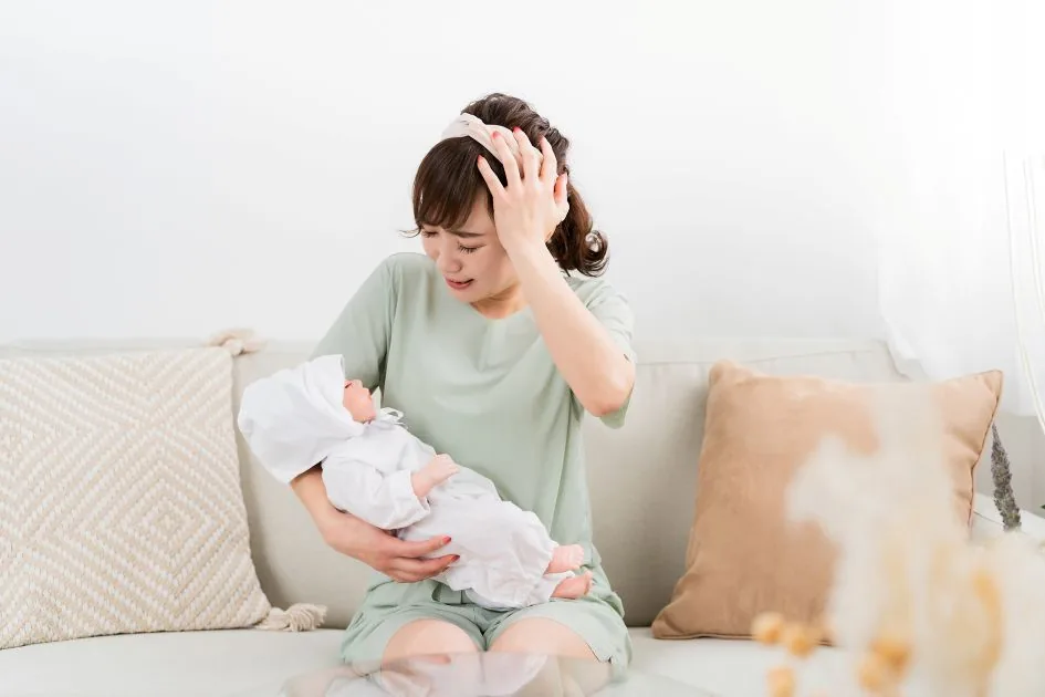 赤ちゃんを抱いて途方に暮れる母親