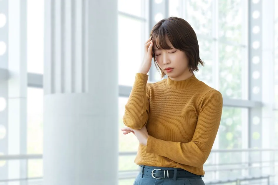 額に手を当てて悩む女性