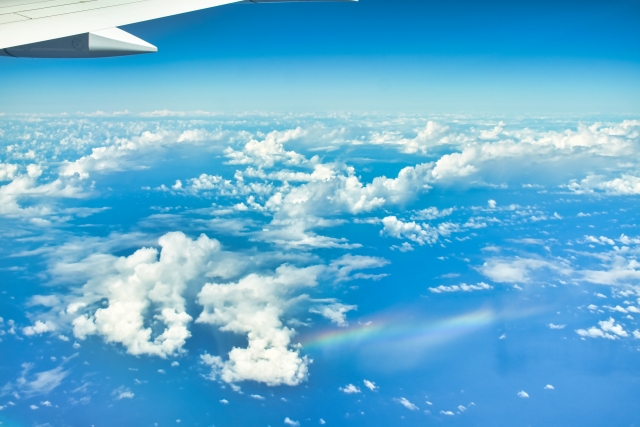 飛行機の窓から見える雲と虹